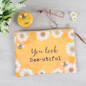 Cosmetic bag with bee and daisy design shown with makeup accessories