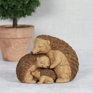 Resin hedgehog family ornament showing two parent hedgehogs cuddling their baby