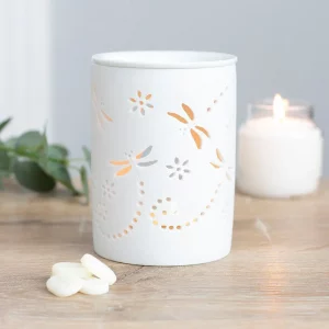 White ceramic dragonfly cut-out oil burner with tealight candle glowing through floral design.