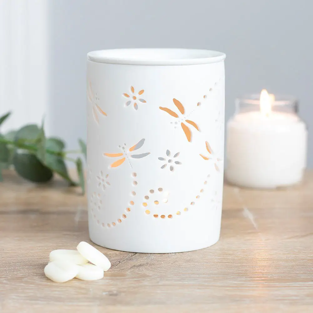 White ceramic dragonfly cut-out oil burner with tealight candle glowing through floral design.