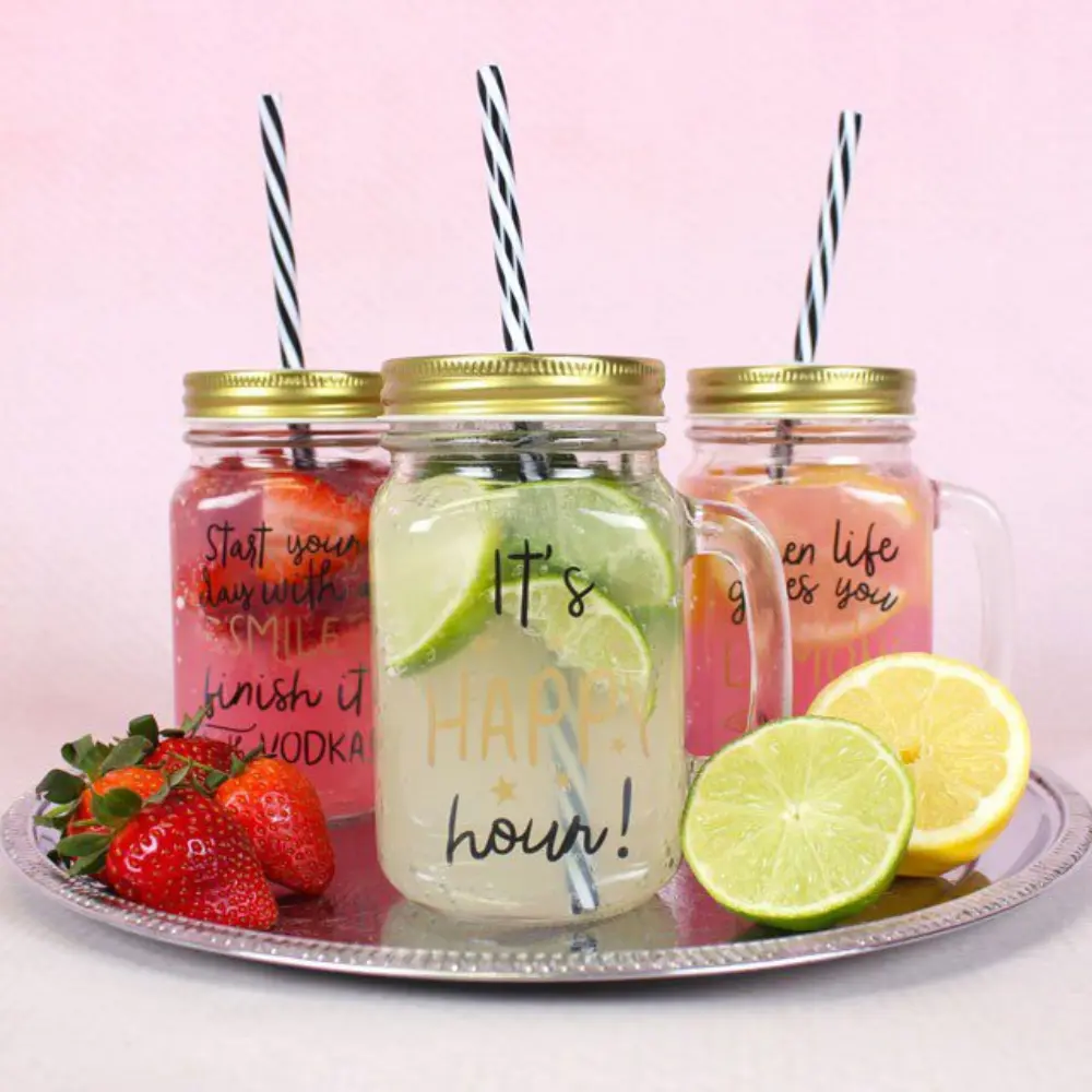Glass jar with gold lid and black-and-white straw filled with lemon drink