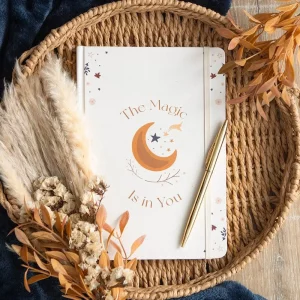 Flat lay of celestial notebook styled with pen and dried flowers