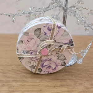 Set of four round floral coasters tied with jute and a pink button, featuring soft pink rose designs