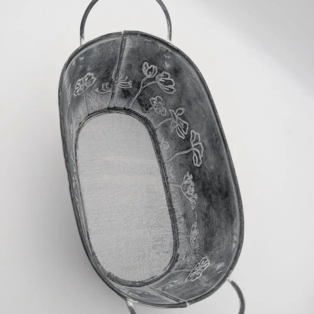 Oval grey metal plant pot with embossed flower design