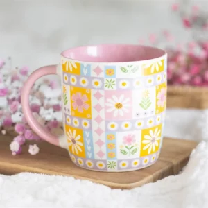 Floral patchwork ceramic mug styled with soft pink flowers in background