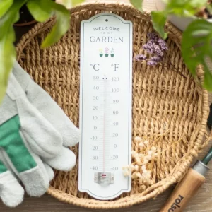 Welcome to My Garden wall thermometer displayed in a woven basket with gardening gloves and tools
